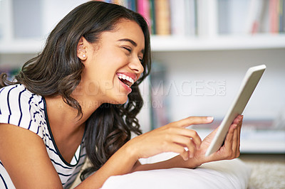 Buy stock photo Cropped shot of a young woman using her tablet while relaxing at home