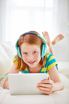 Buy stock photo Shot of a little girl using a digital tablet with headphones at home