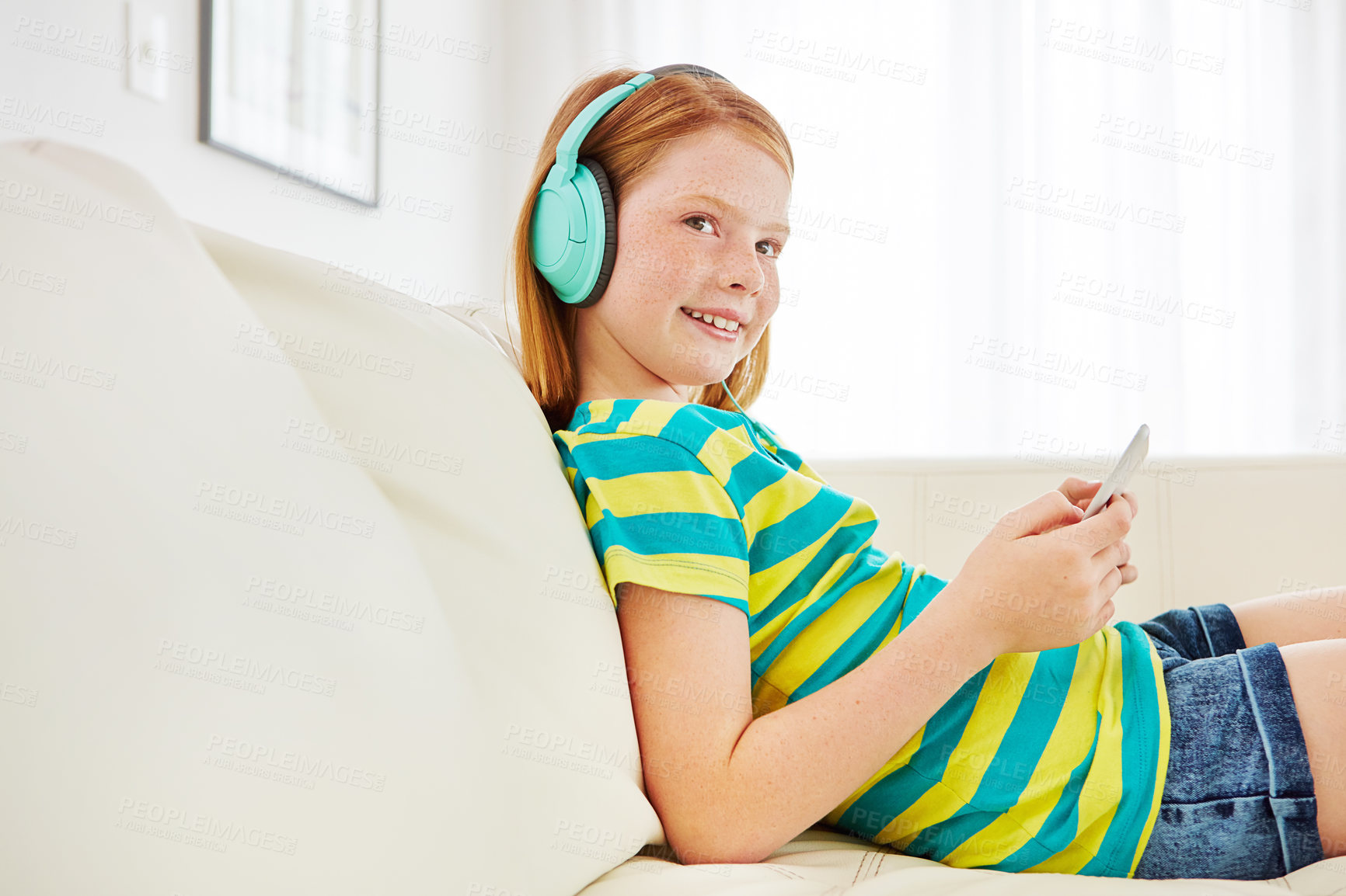 Buy stock photo Shot of a little girl using a digital tablet with headphones at home