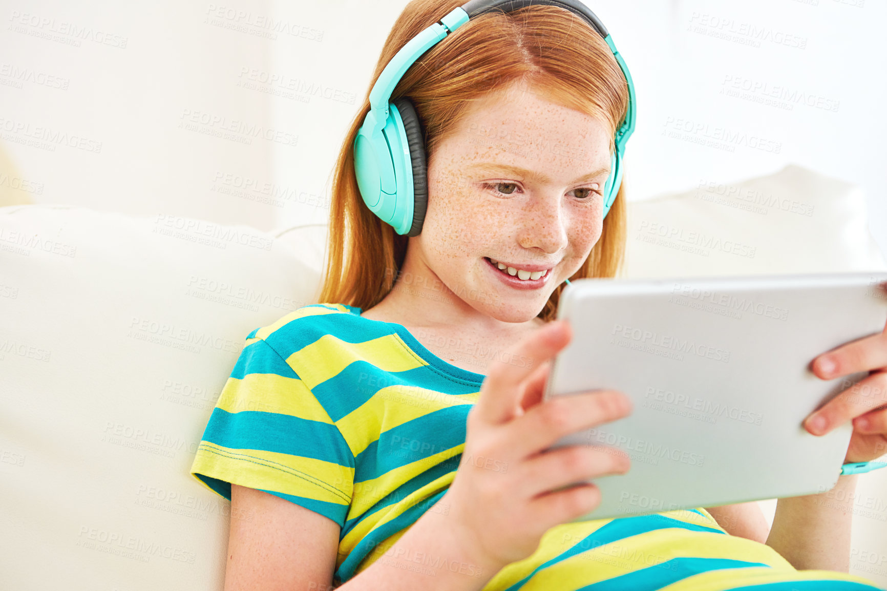 Buy stock photo Shot of a little girl using a digital tablet with headphones at home