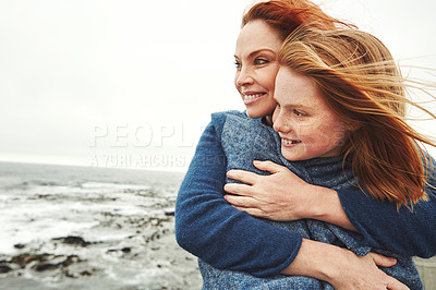 Buy stock photo Shot of a mature woman embracing her young daughter at the waterfront