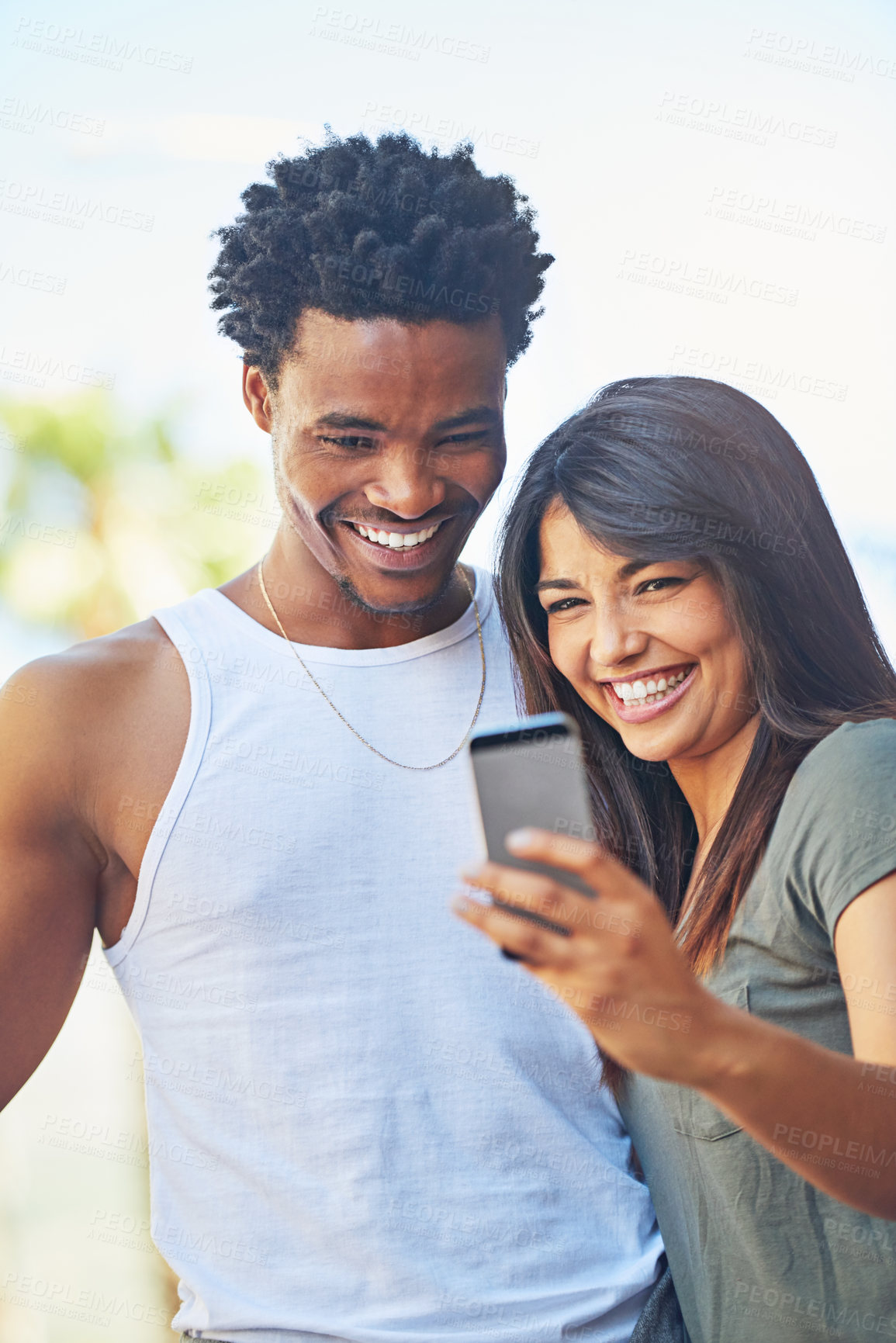 Buy stock photo Shot of a happy young couple using a mobile phone together