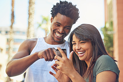 Buy stock photo Shot of a happy young couple using a mobile phone together