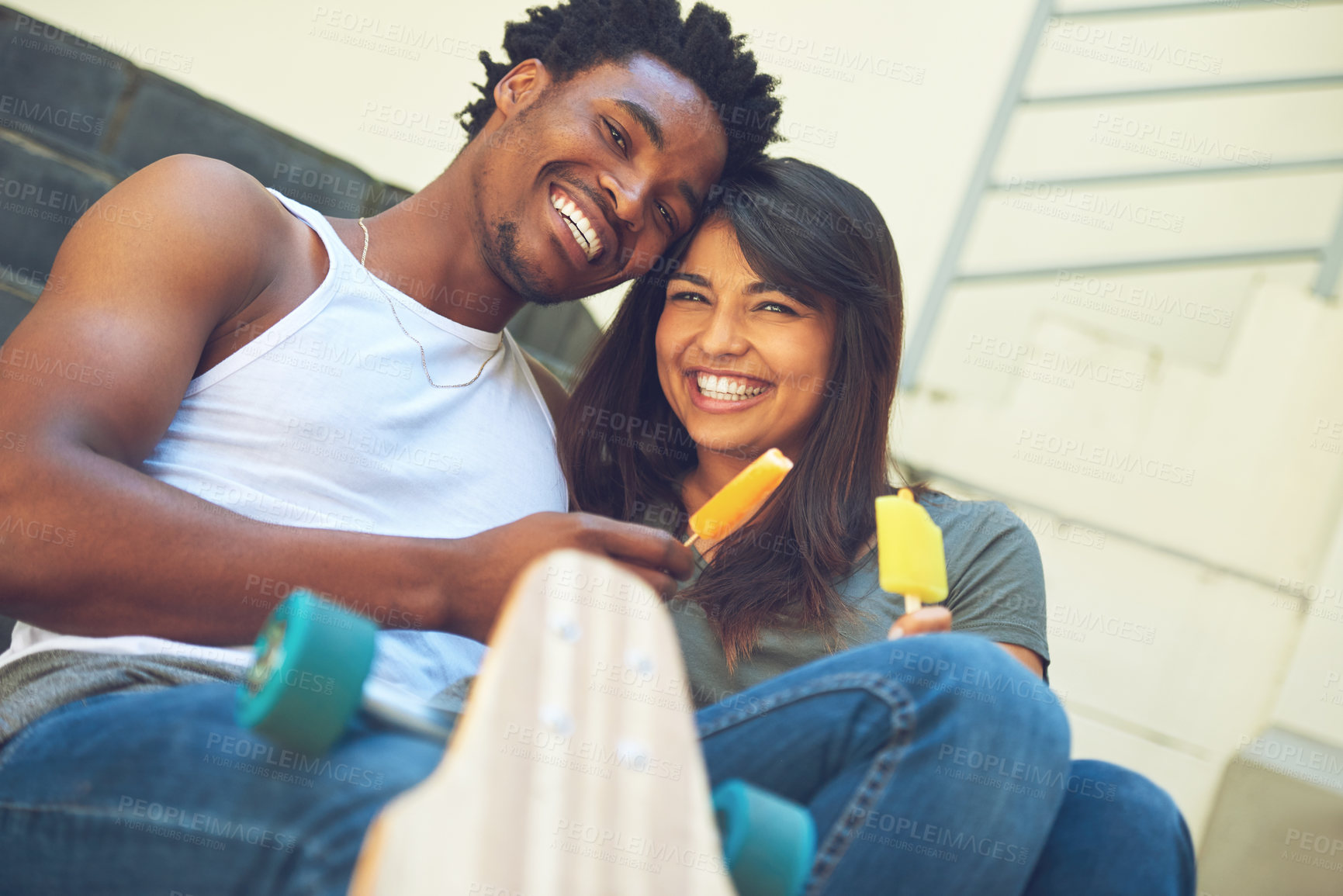 Buy stock photo Shot of a happy young couple eating ice lollies together