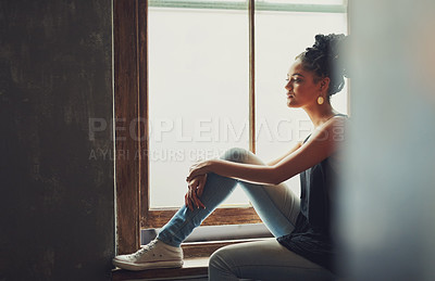 Buy stock photo Shot of an attractive young woman sitting by the window