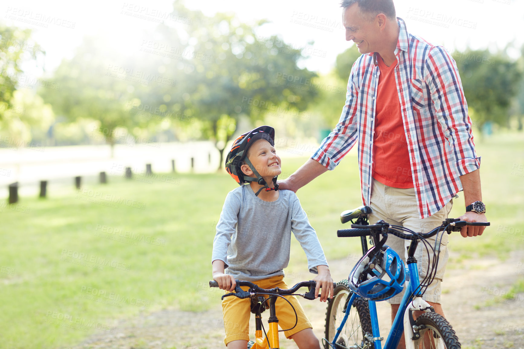 Buy stock photo Shot of a father and son riding bicycles in a park