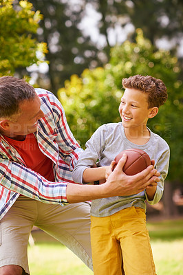 Buy stock photo Shot of a father and son playing football in a park