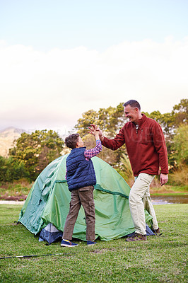Buy stock photo Shot of a father and son hi fiving after setting up a tent together while camping