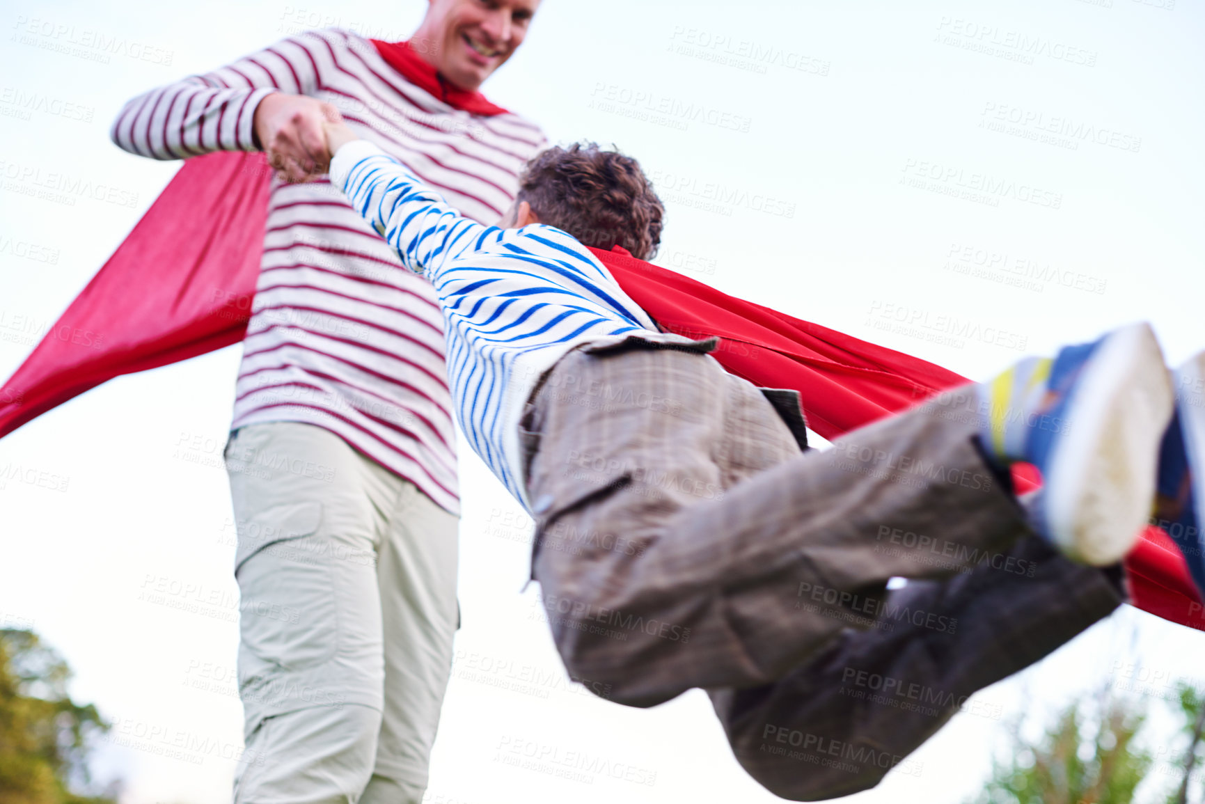 Buy stock photo Shot of a father and his young son pretending to be superheroes while playing outdoors