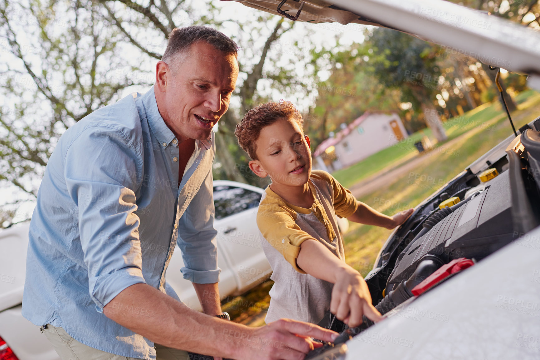 Buy stock photo Shot of a father showing his young son the engine of a car