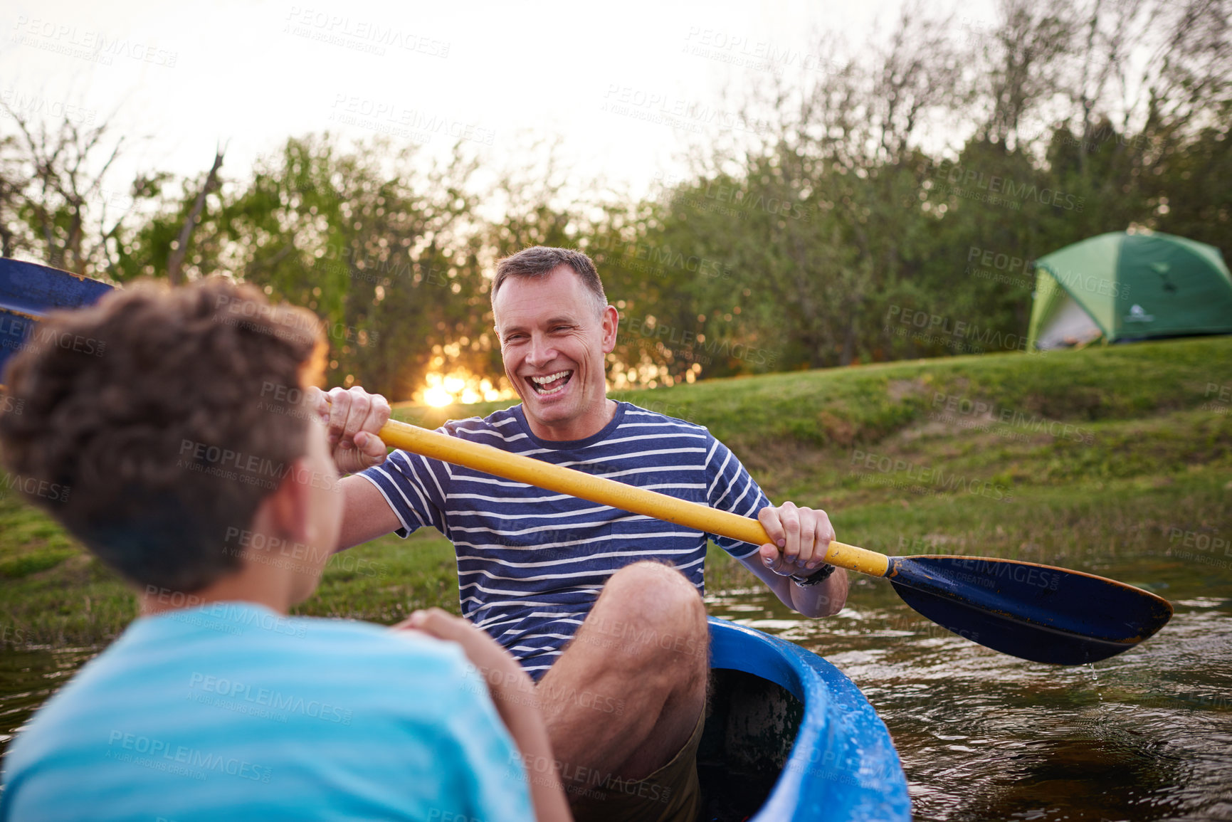 Buy stock photo Shot of a father and son rowing a boat together on a lake