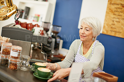 Buy stock photo Shot of a senior woman serving coffee in a cafe