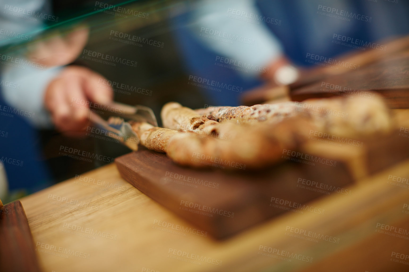 Buy stock photo Cropped shot of a deli worker choosing a bread stick from the display