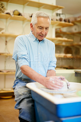 Buy stock photo Shot of a senior man making a ceramic pot in a workshop