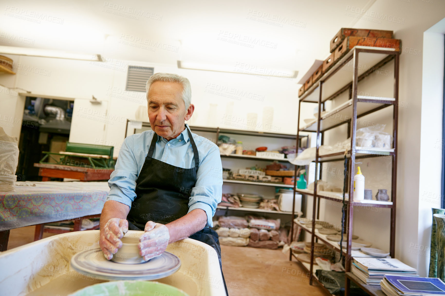 Buy stock photo Shot of a senior man making a ceramic pot in a workshop