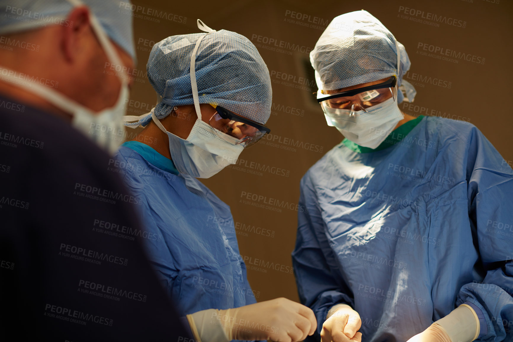 Buy stock photo Shot of a team of surgeons performing a surgical procedure in an operating room