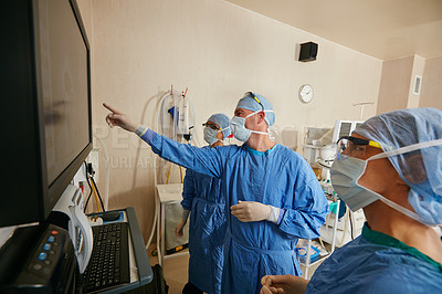 Buy stock photo Shot of a team of surgeons discussing a patient’s medical scans during surgery