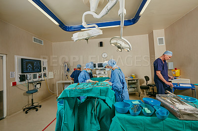 Buy stock photo Shot of a team of surgeons performing a surgery in an operating room