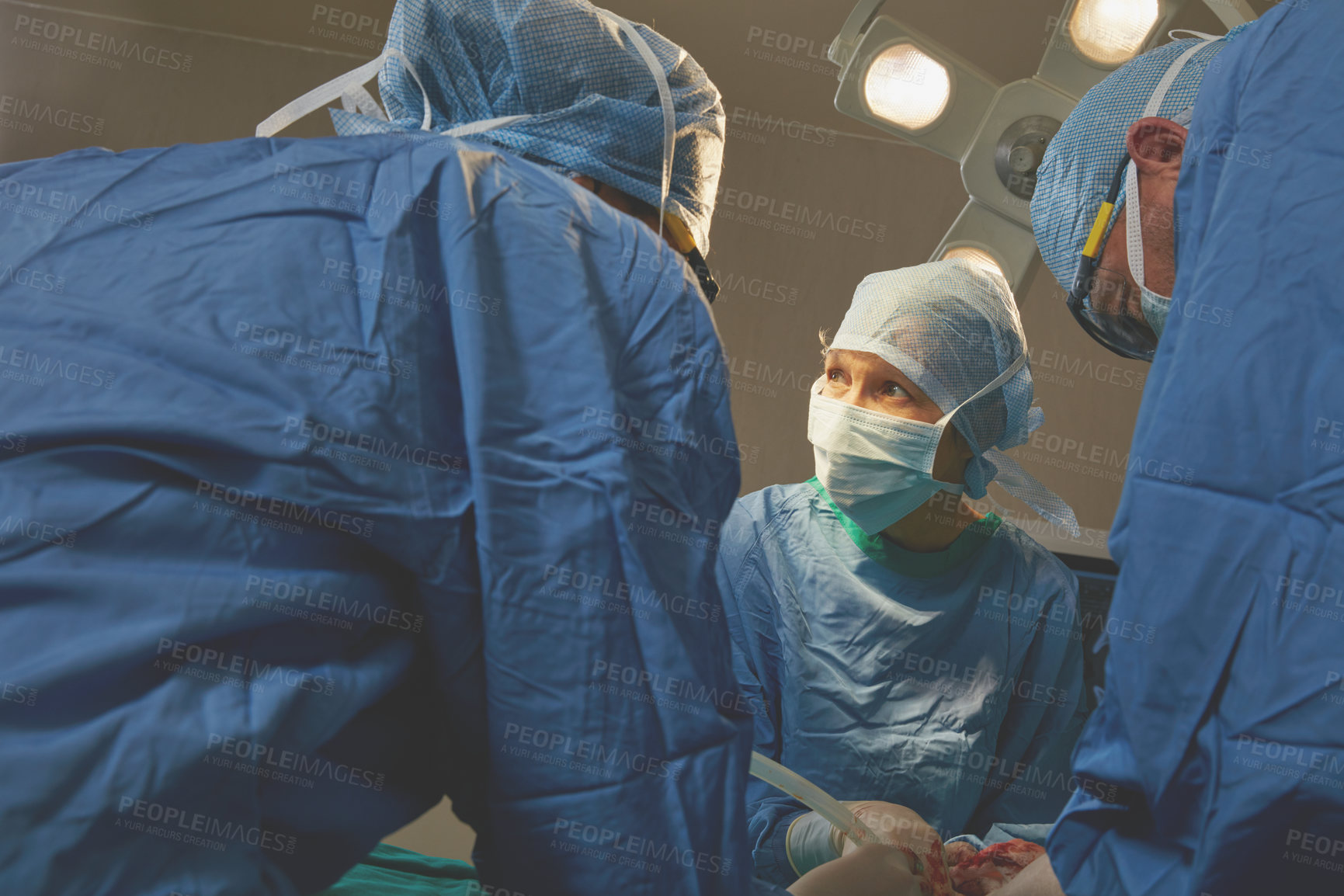 Buy stock photo Shot of a team of surgeons performing a surgery in an operating room