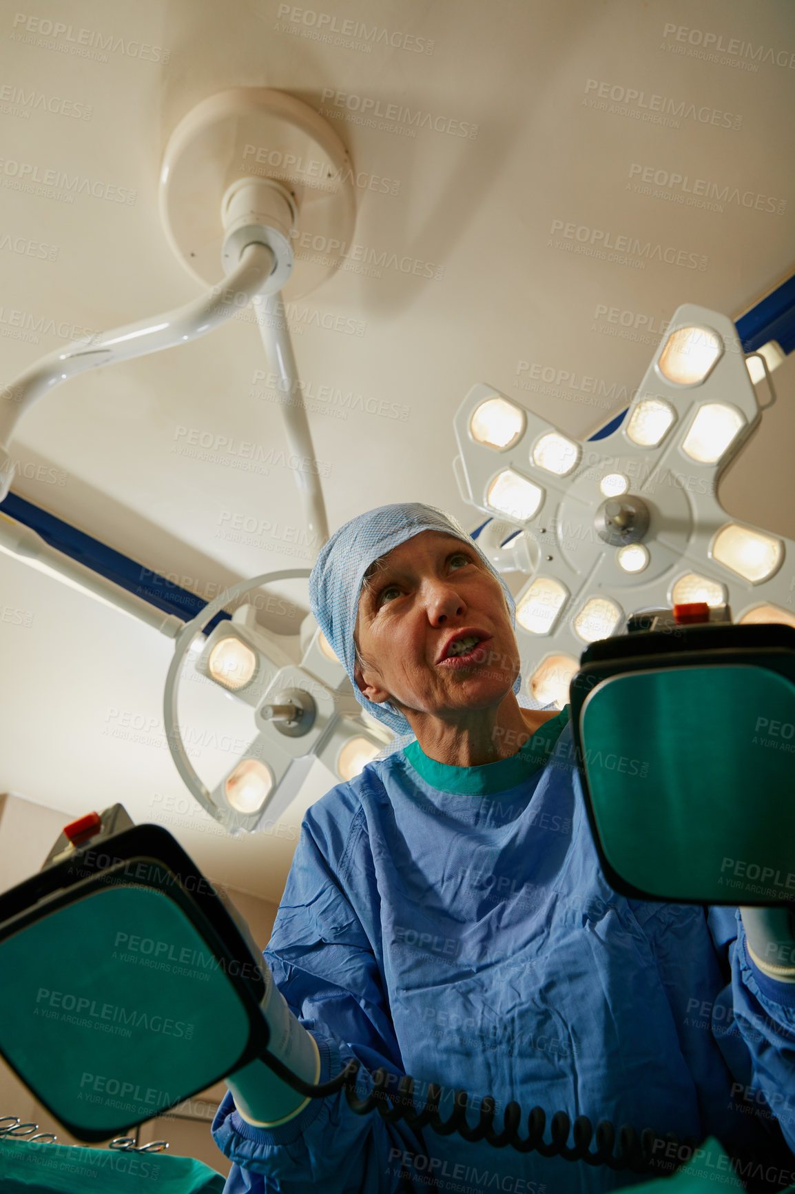 Buy stock photo Shot of a surgeon using a defibrillator during surgery