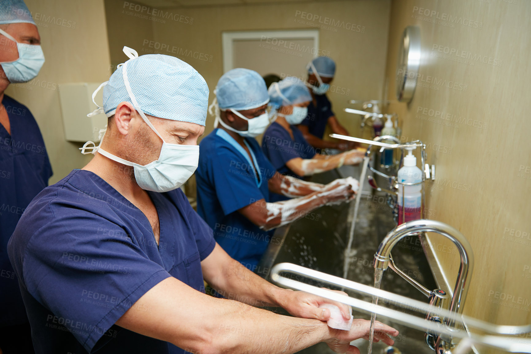 Buy stock photo Shot of a team of surgeons sterilizing their arms and hands as part of a surgical routine
