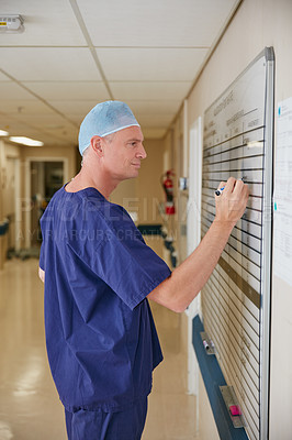 Buy stock photo Cropped shot of a male doctor writing on a whiteboard in the hospital
