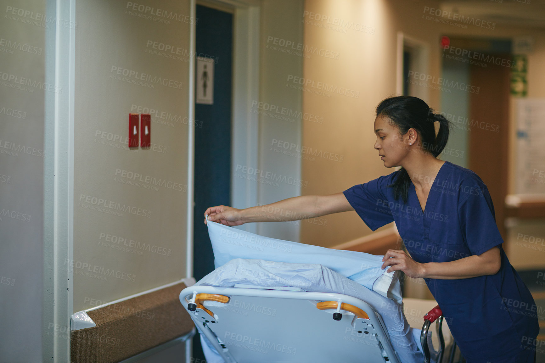 Buy stock photo Cropped shot of a female nurse making up a hospital bed