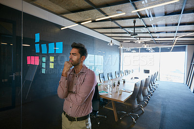 Buy stock photo Shot of a young businessman looking at sticky notes on a glass wall