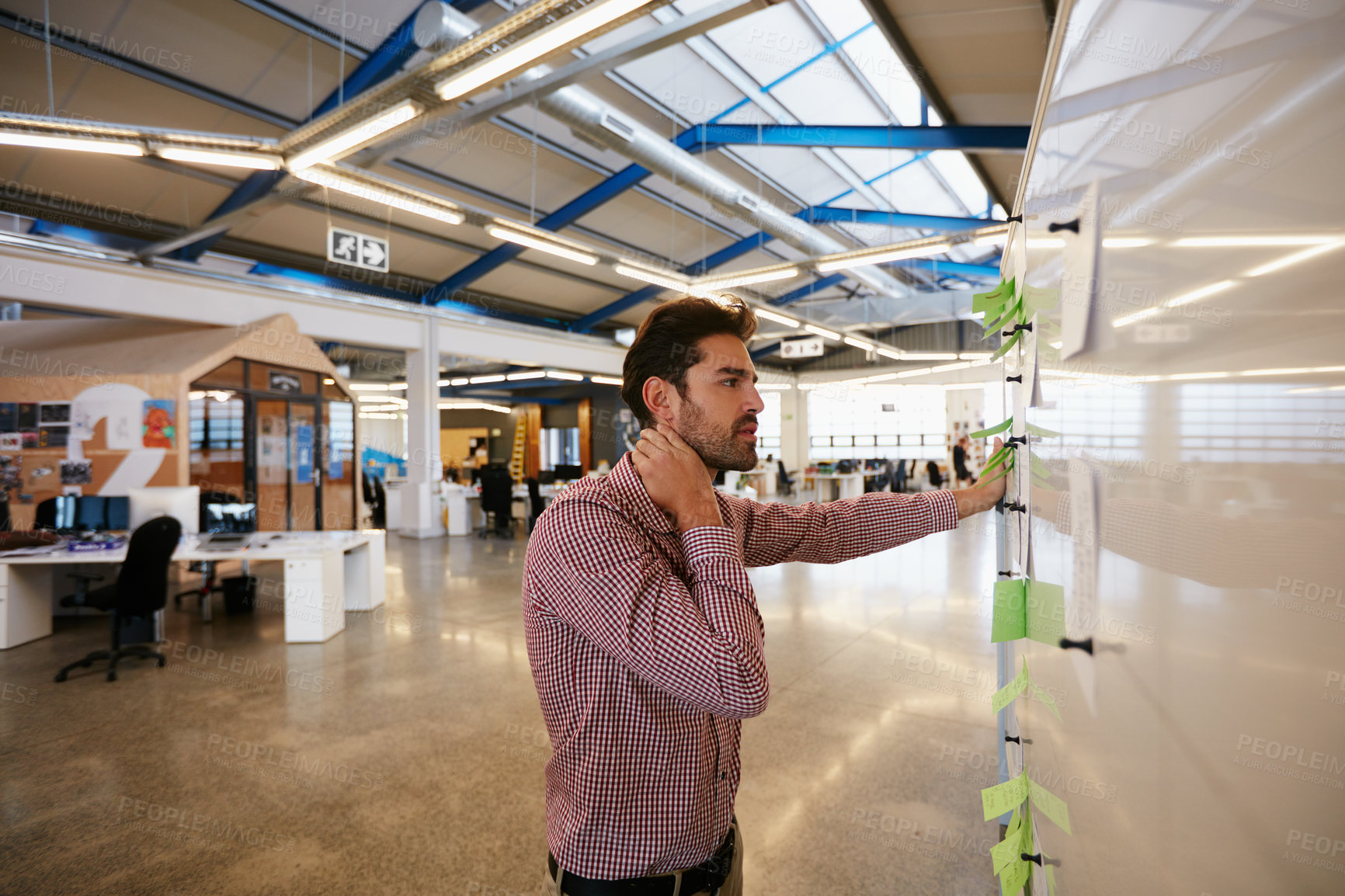 Buy stock photo Shot of a young businessman looking at sticky notes on a whiteboard