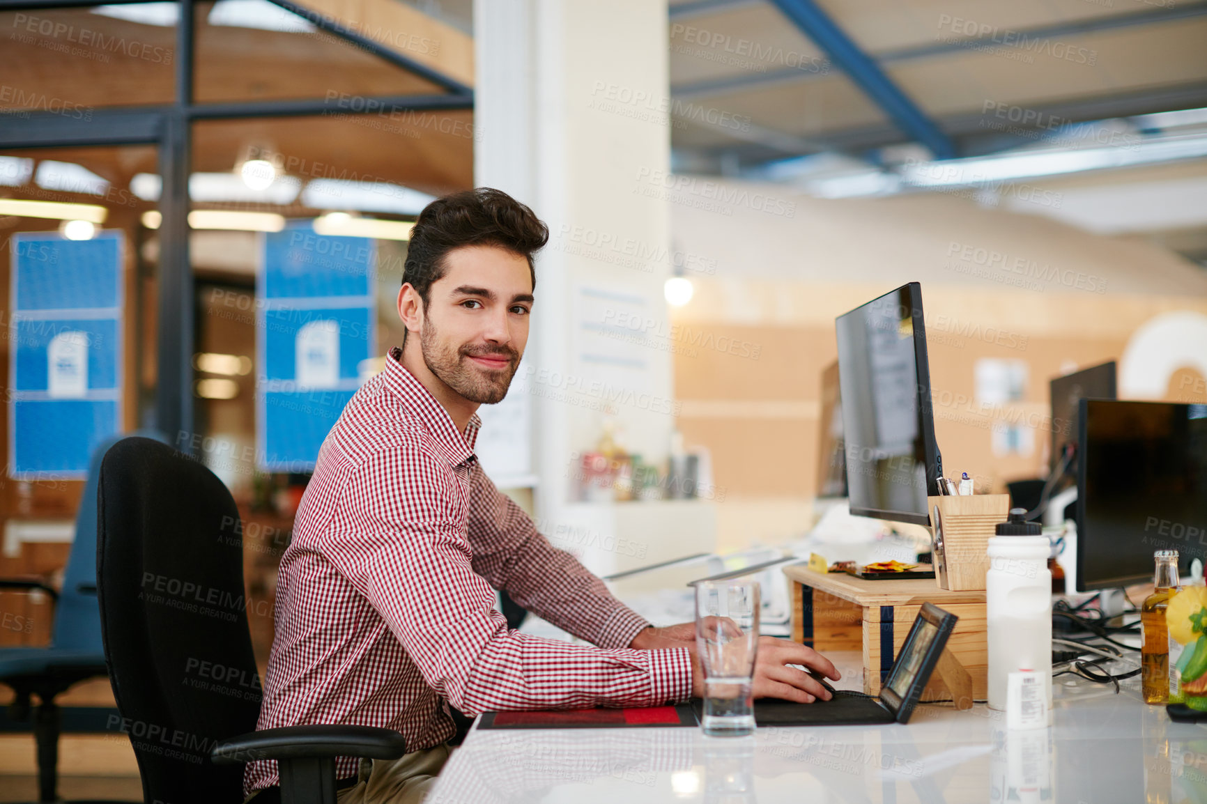Buy stock photo Shot of a young businessman sitting at his desk