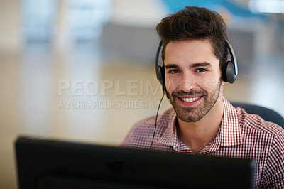 Buy stock photo Shot of a friendly young call centre agent sitting at his desk