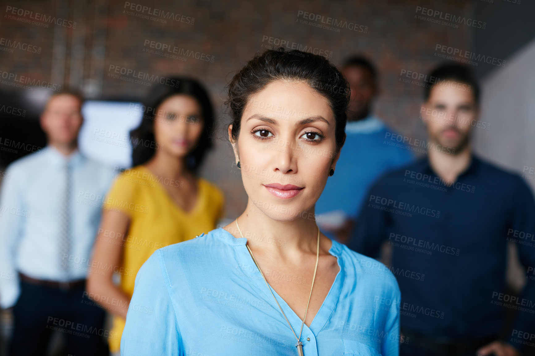 Buy stock photo Cropped portrait of a businesswoman standing in the workplace with her colleagues in the background