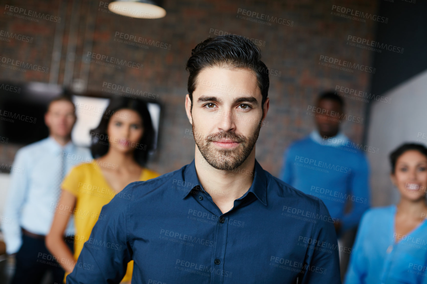 Buy stock photo Cropped portrait of a businessman standing in the workplace with his colleagues in the background