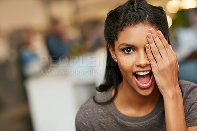 Buy stock photo Portrait of a playful young woman covering her eye in a modern office