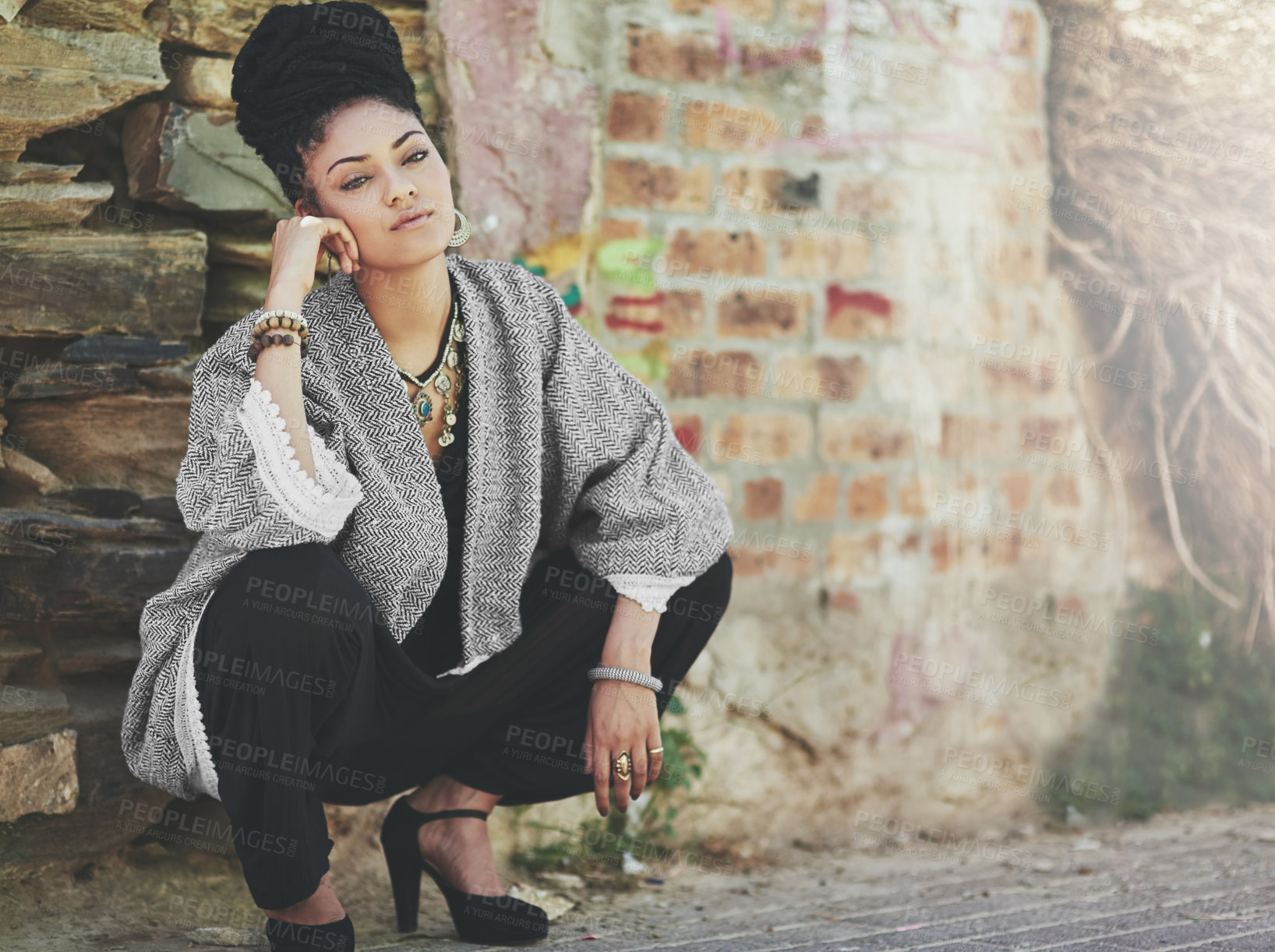 Buy stock photo Full length shot of a fashionable young woman crouching against a wall