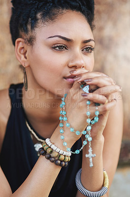 Buy stock photo Shot of an attractive young woman praying with her rosary outdoors
