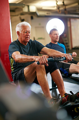 Buy stock photo Cropped shot of two men working out on the rowing machine at the gym