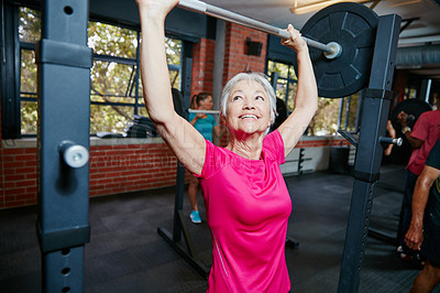 Buy stock photo Shot of a senior woman lifting weights at the gym