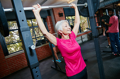 Buy stock photo Shot of a senior woman lifting weights at the gym