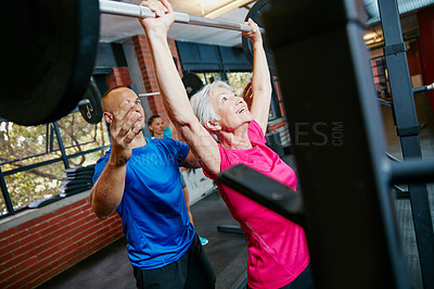 Buy stock photo Shot of a senior woman lifting weights with her fitness instructor guiding her