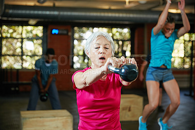 Buy stock photo Shot of a senior woman working out with a kettle bell at the gym