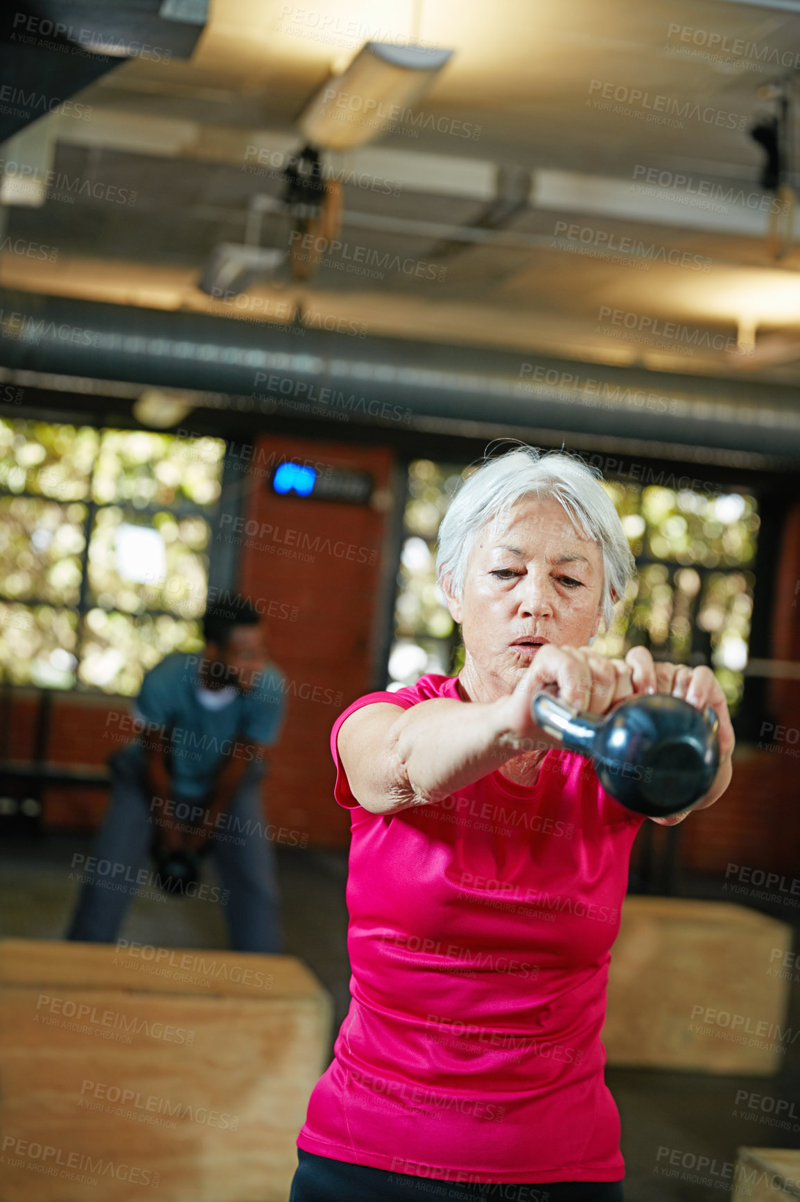 Buy stock photo Shot of a senior woman working out with a kettle bell at the gym