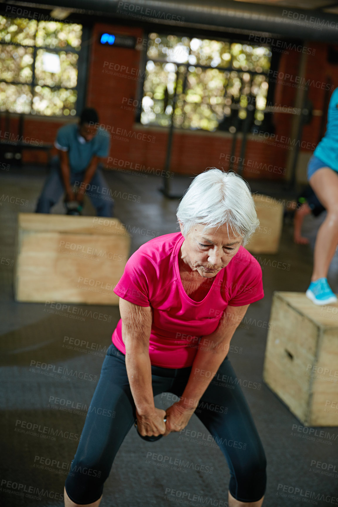 Buy stock photo Shot of a senior woman working out with a kettle bell at the gym