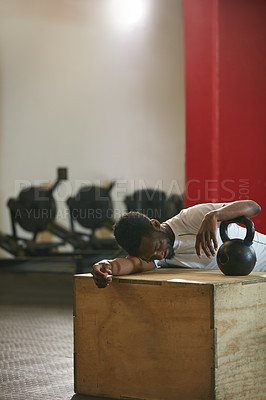 Buy stock photo Shot of a young man taking a break from an exhausting kettle bell workout
