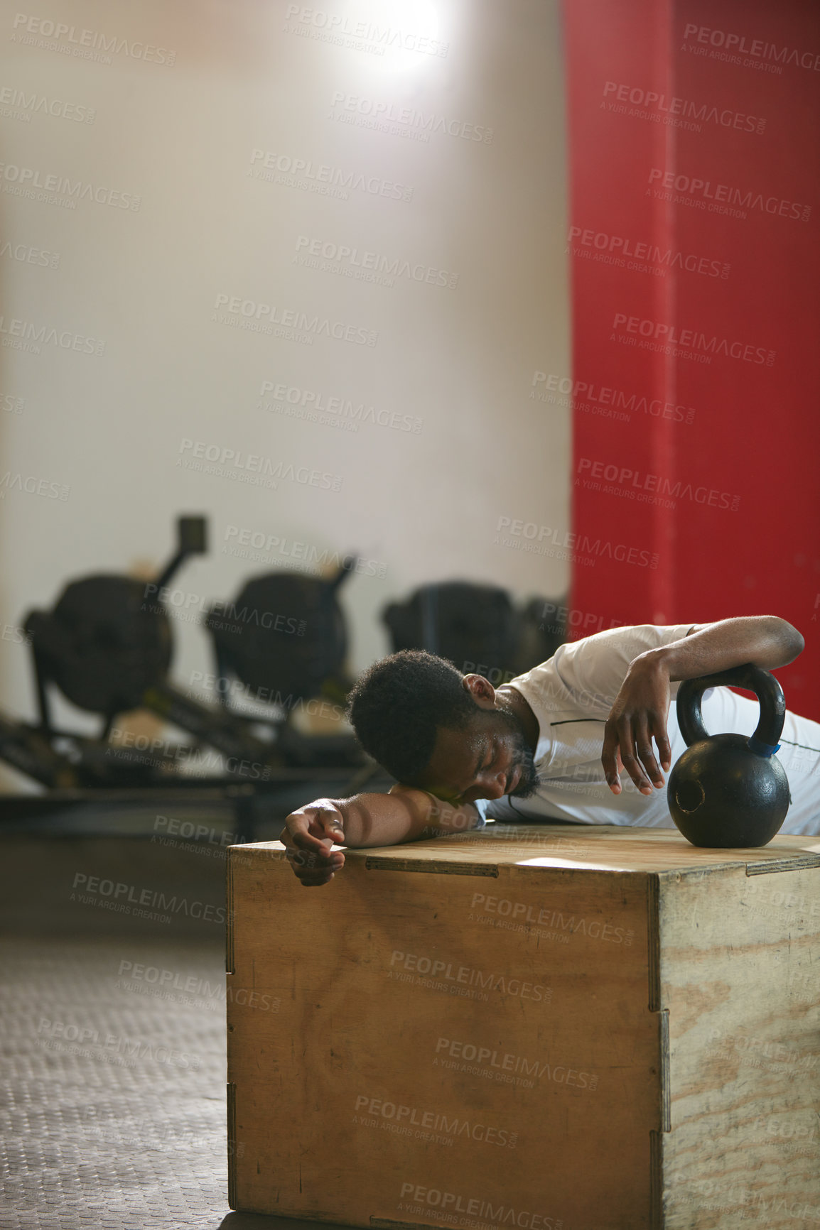 Buy stock photo Shot of a young man taking a break from an exhausting kettle bell workout