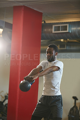 Buy stock photo Shot of a young man working out with a kettle bell at the gym