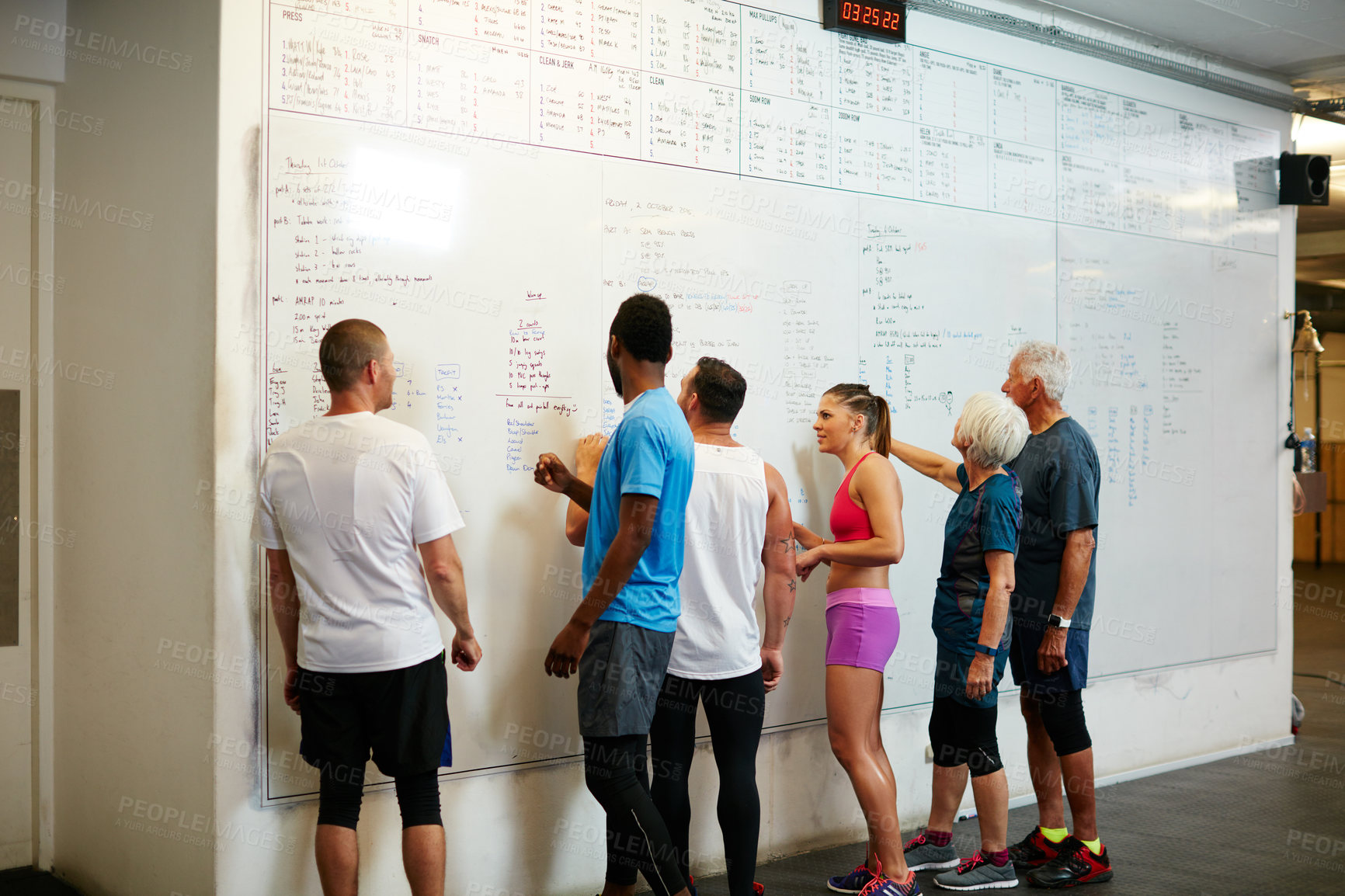 Buy stock photo Rearview shot of a group of people looking at a whiteboard while standing in the gym