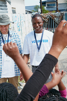 Buy stock photo Cropped shot of volunteer workers addressing a group of children at a community outreach event