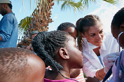 Buy stock photo Cropped shot of a female doctor doing medical tests on children at a community outreach event