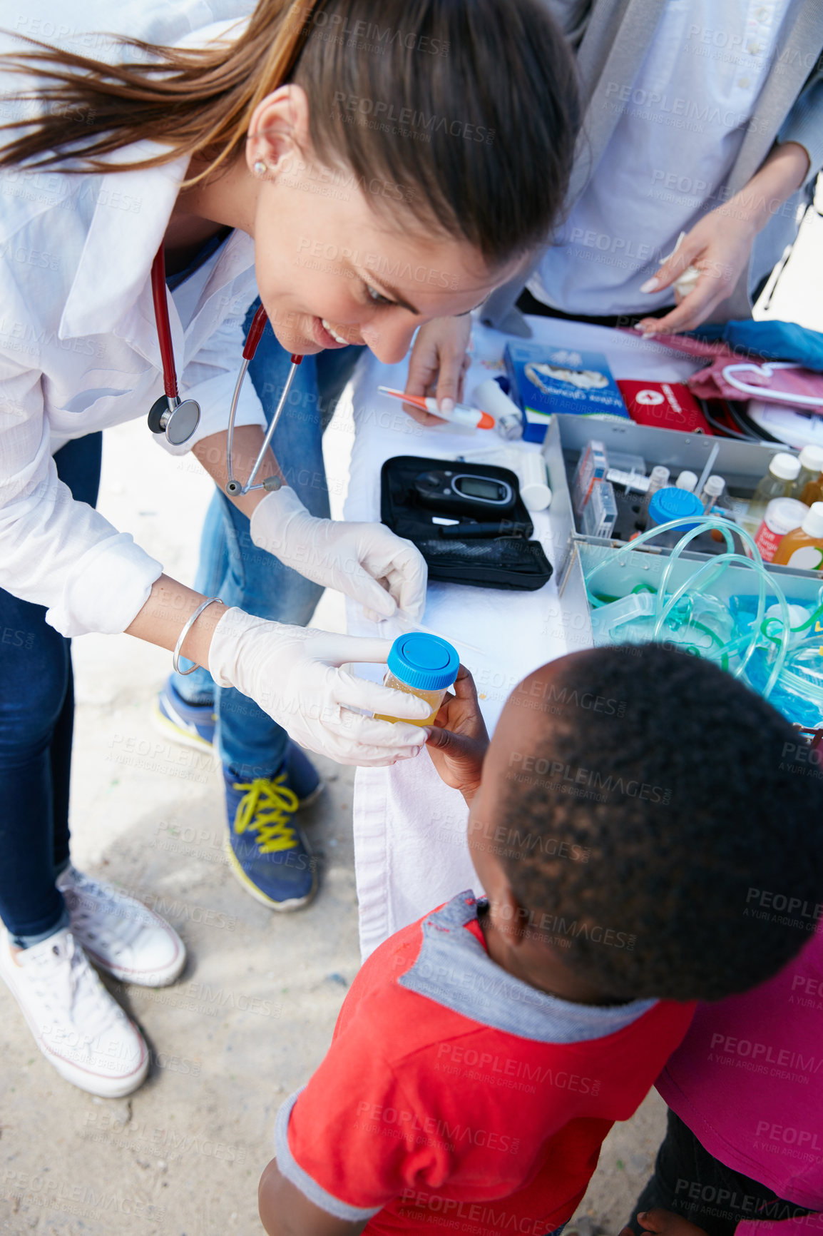 Buy stock photo Shot of a volunteer doctor giving checkups to underprivileged kids